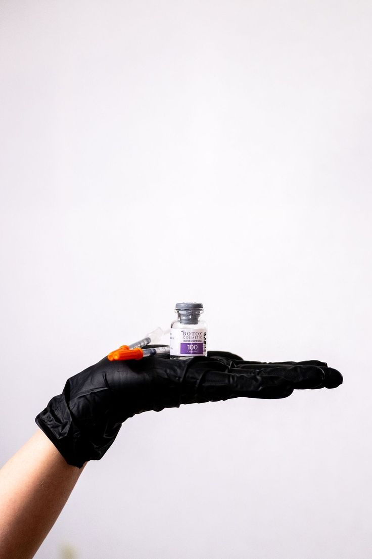 Frasco de toxina botulínica sobre luva preta
